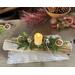 A Christmas yule log centerpiece with a battery candle, oranges slcies, jingle bells and real touch greenery